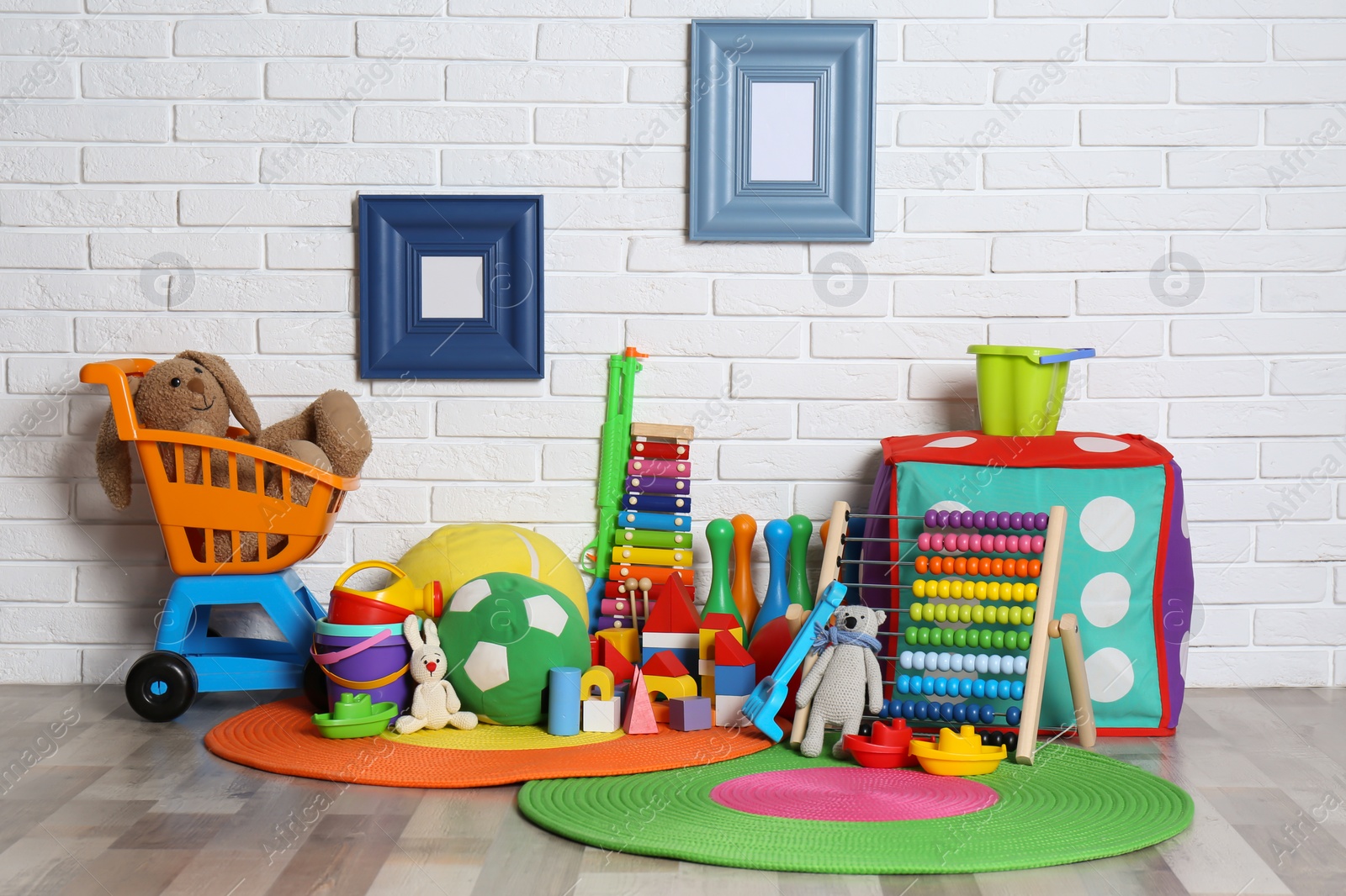 Photo of Different child toys on floor against brick wall