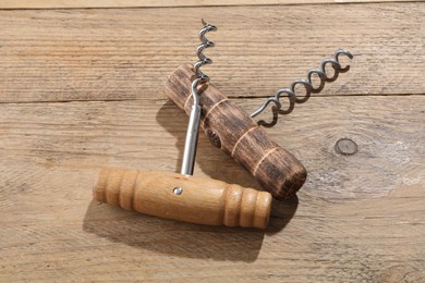 Photo of Two different corkscrews on wooden table. Kitchen utensil