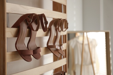 Photo of Rack with stylish women's high heeled shoes in dressing room. Modern interior design