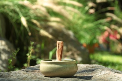 Photo of Palo santo stick in holder on stone outdoors