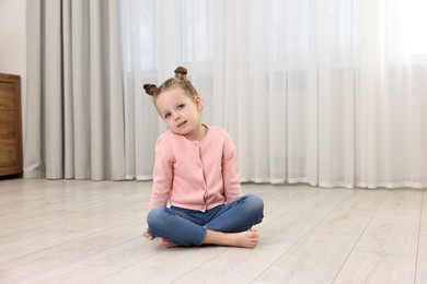 Cute little girl sitting on warm floor at home. Heating system