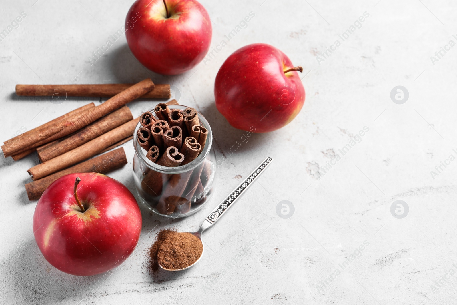 Photo of Fresh apples with cinnamon sticks and powder on table