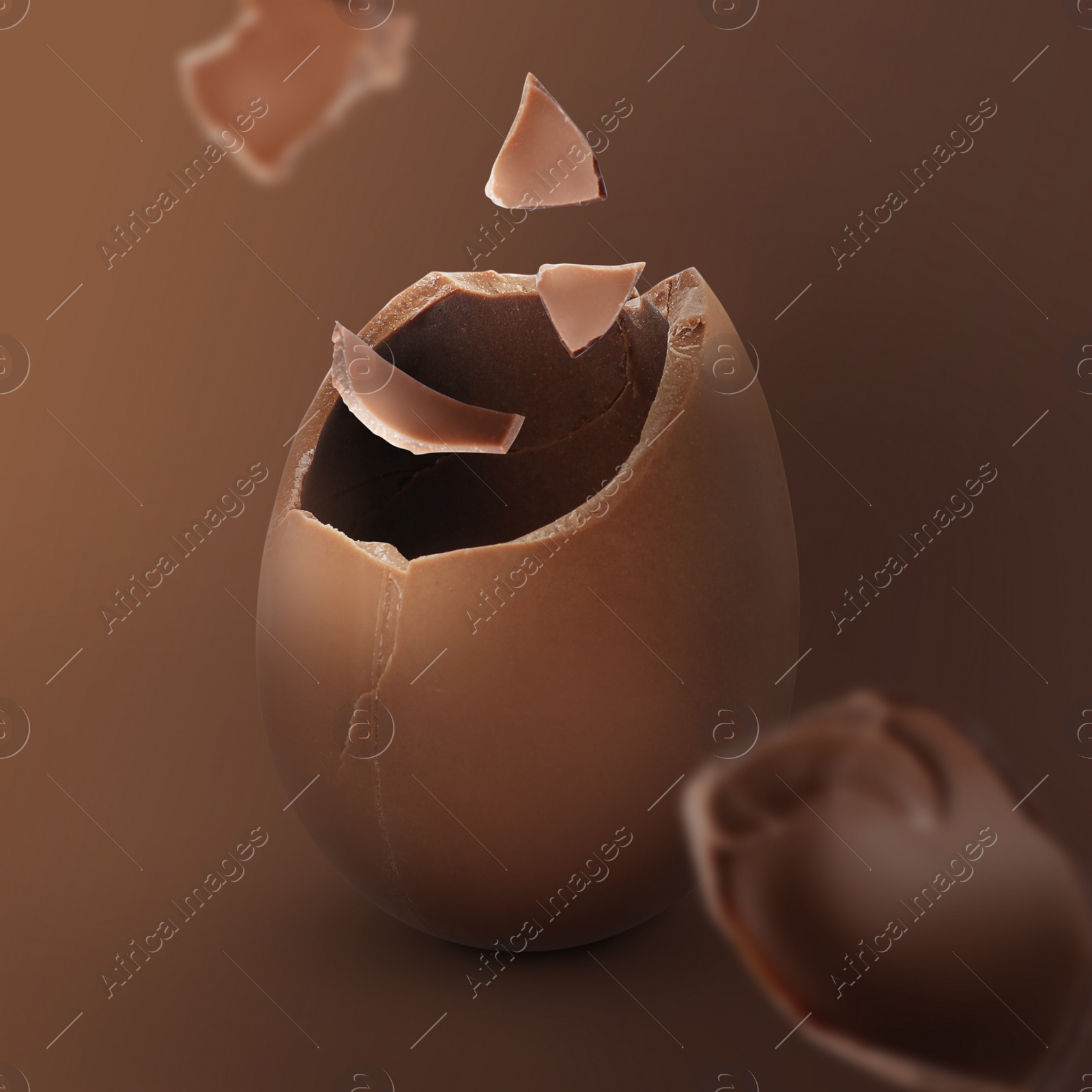 Image of Exploded milk chocolate egg on brown background