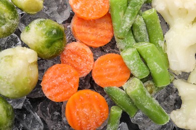 Photo of Different frozen vegetables and ice on black table, flat lay