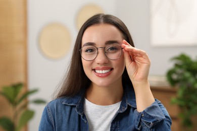 Portrait of beautiful young woman with glasses indoors. Attractive lady smiling and looking into camera