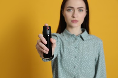 Photo of Young woman using pepper spray on yellow background