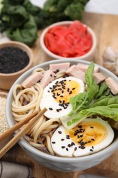 Photo of Bowl of delicious ramen with meat and egg on wooden board, closeup. Noodle soup