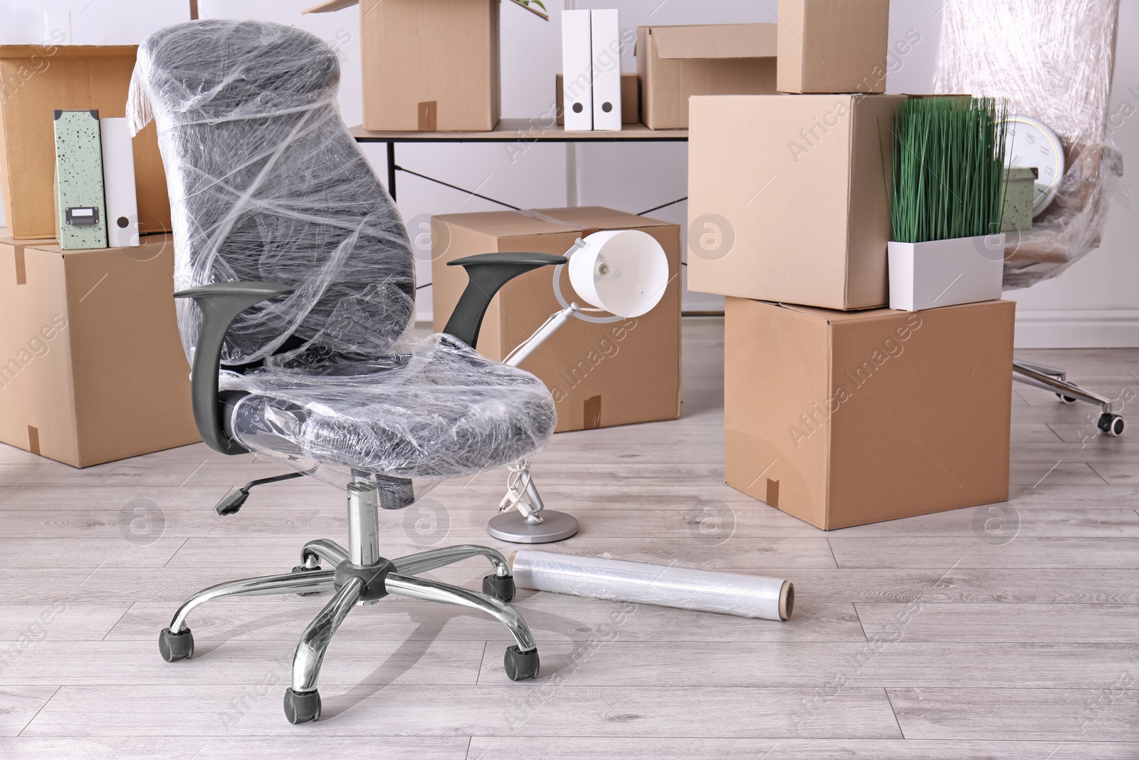 Photo of Armchair and carton boxes with stuff in room. Office move concept