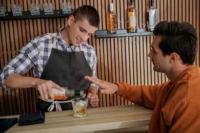 Bartender pouring whiskey for client at counter in pub