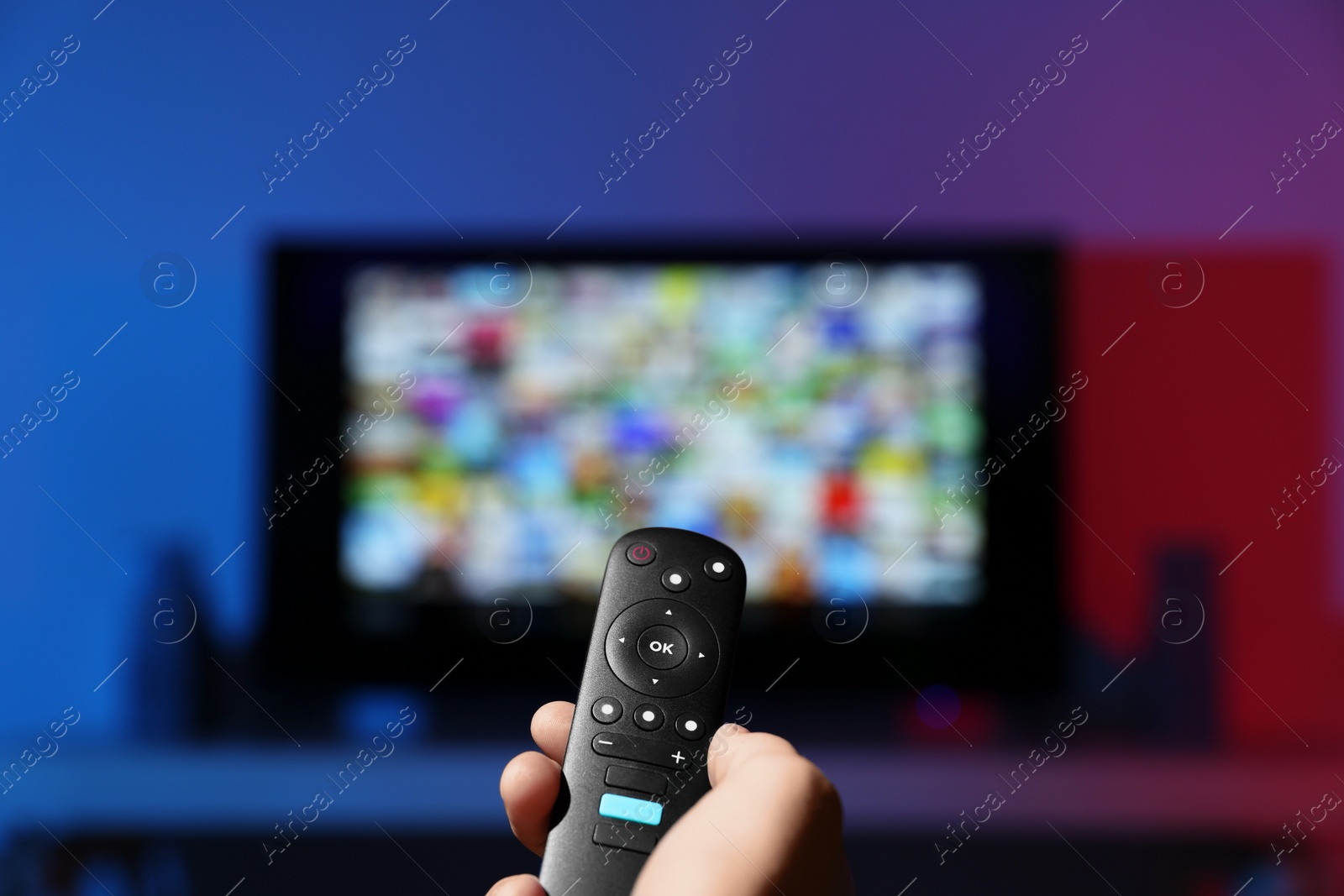 Photo of Woman switching channels on TV set with remote control at home, closeup