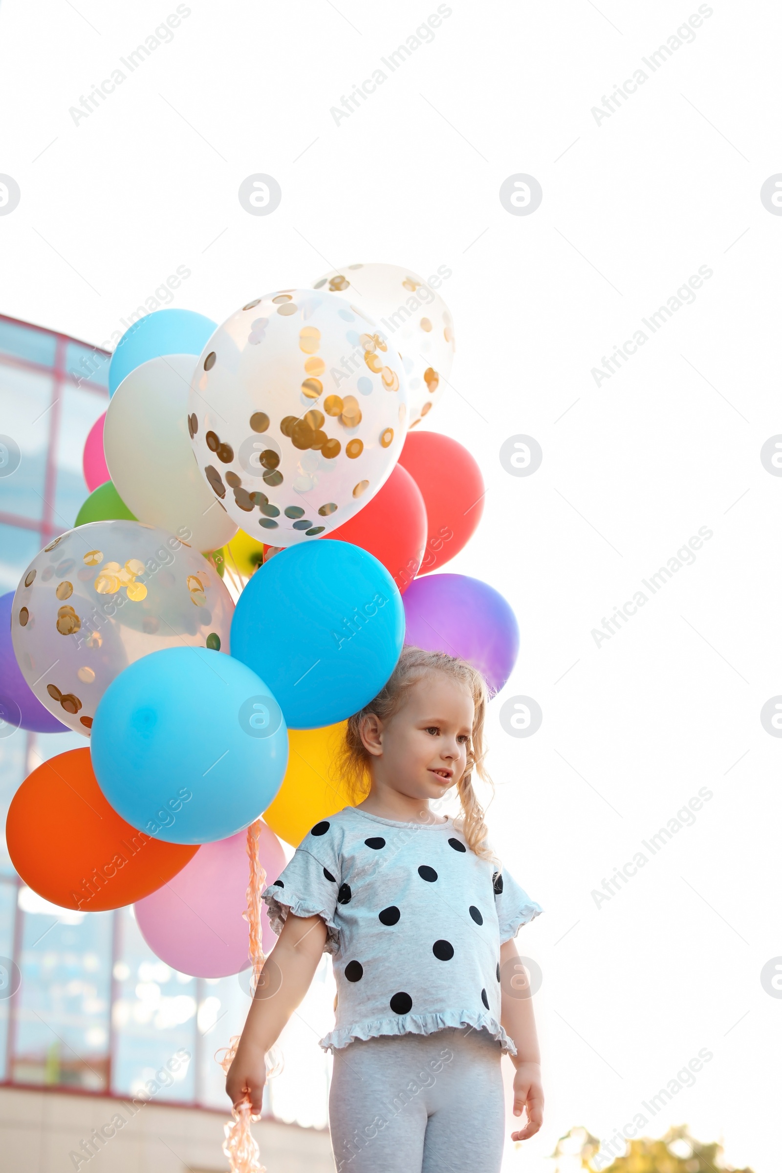 Photo of Cute little girl with colorful balloons outdoors on sunny day