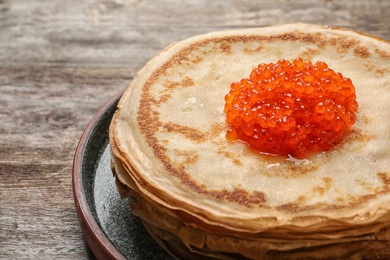 Photo of Thin pancakes with delicious red caviar on table