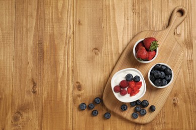 Photo of Yogurt served with berries on wooden table, top view. Space for text