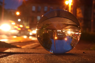 Beautiful city street, overturned reflection. Crystal ball on asphalt road at night, closeup