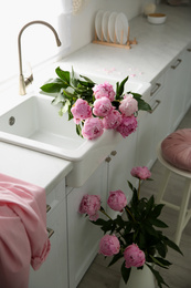 Photo of Beautiful pink peonies in stylish kitchen interior