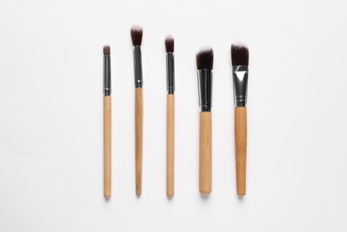 Photo of Different makeup brushes on white background, flat lay