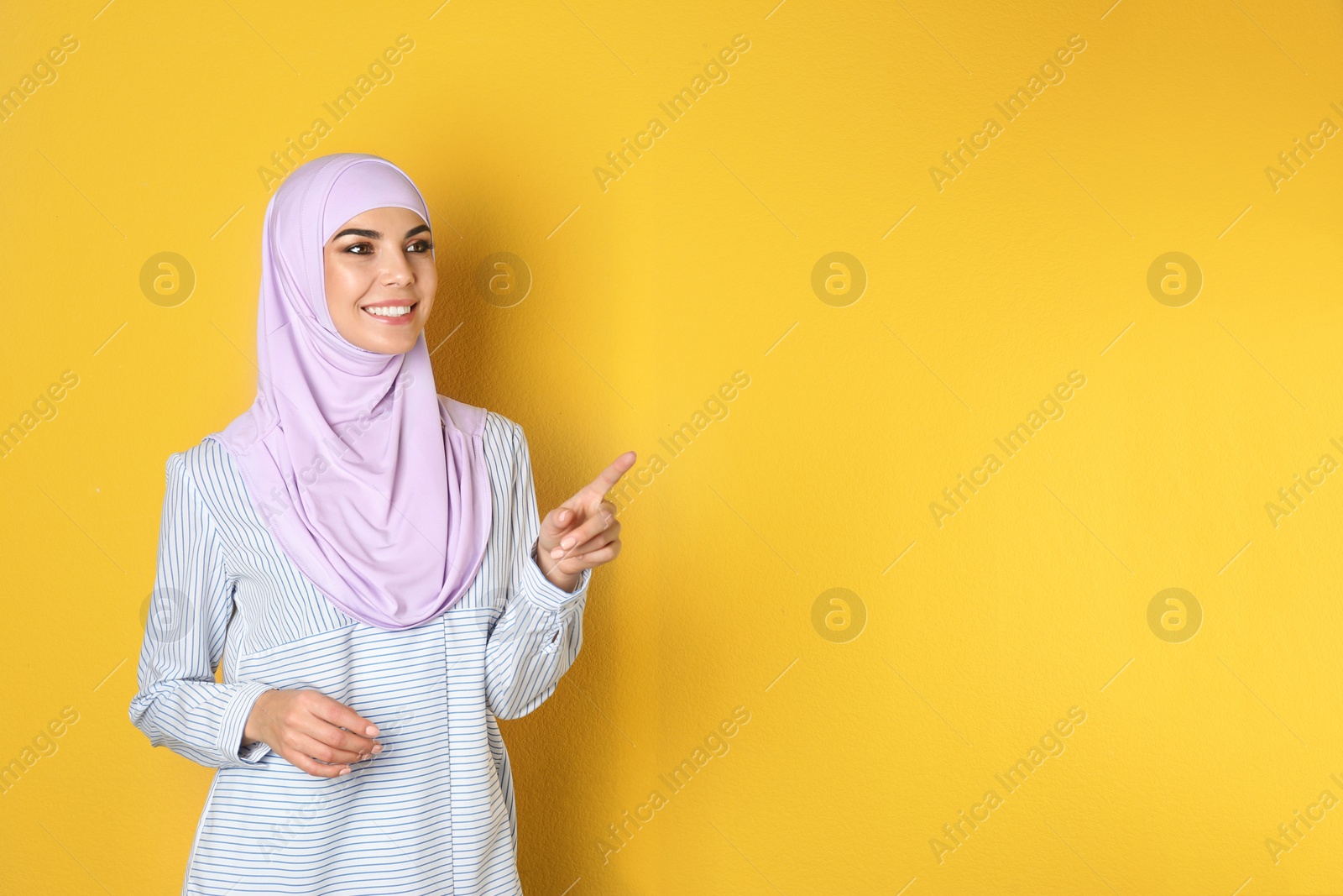 Photo of Portrait of young Muslim woman in hijab against color background. Space for text