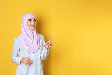 Photo of Portrait of young Muslim woman in hijab against color background. Space for text