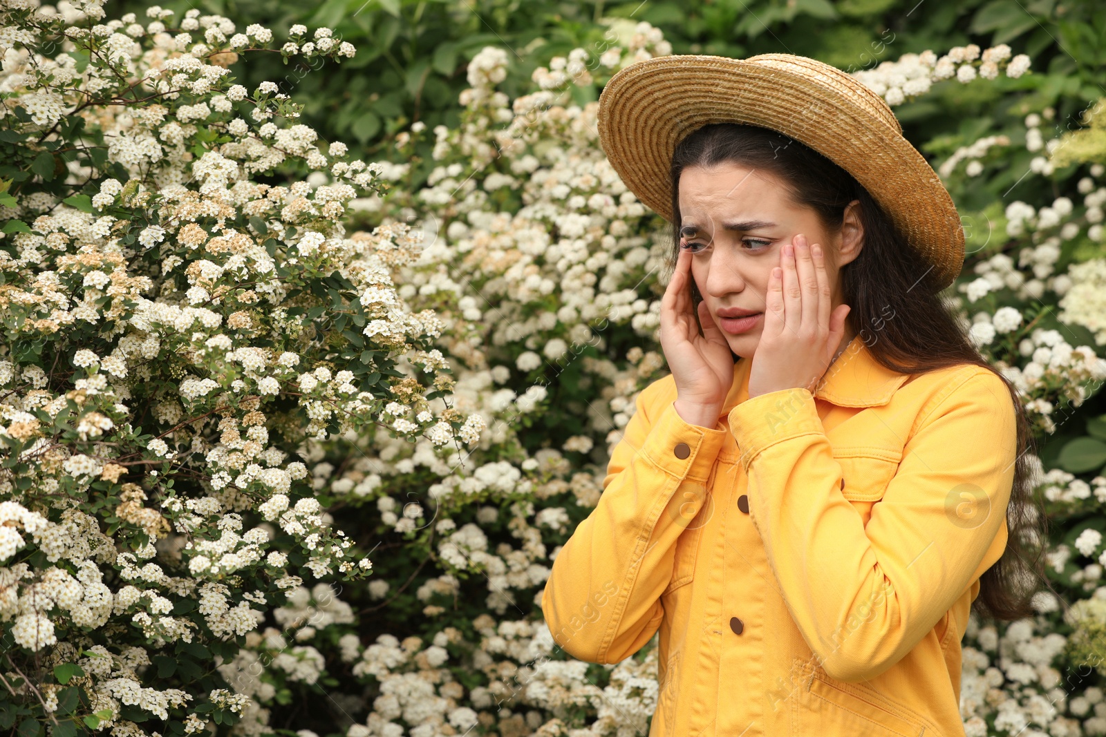 Photo of Woman suffering from seasonal pollen allergy near blossoming tree on spring day