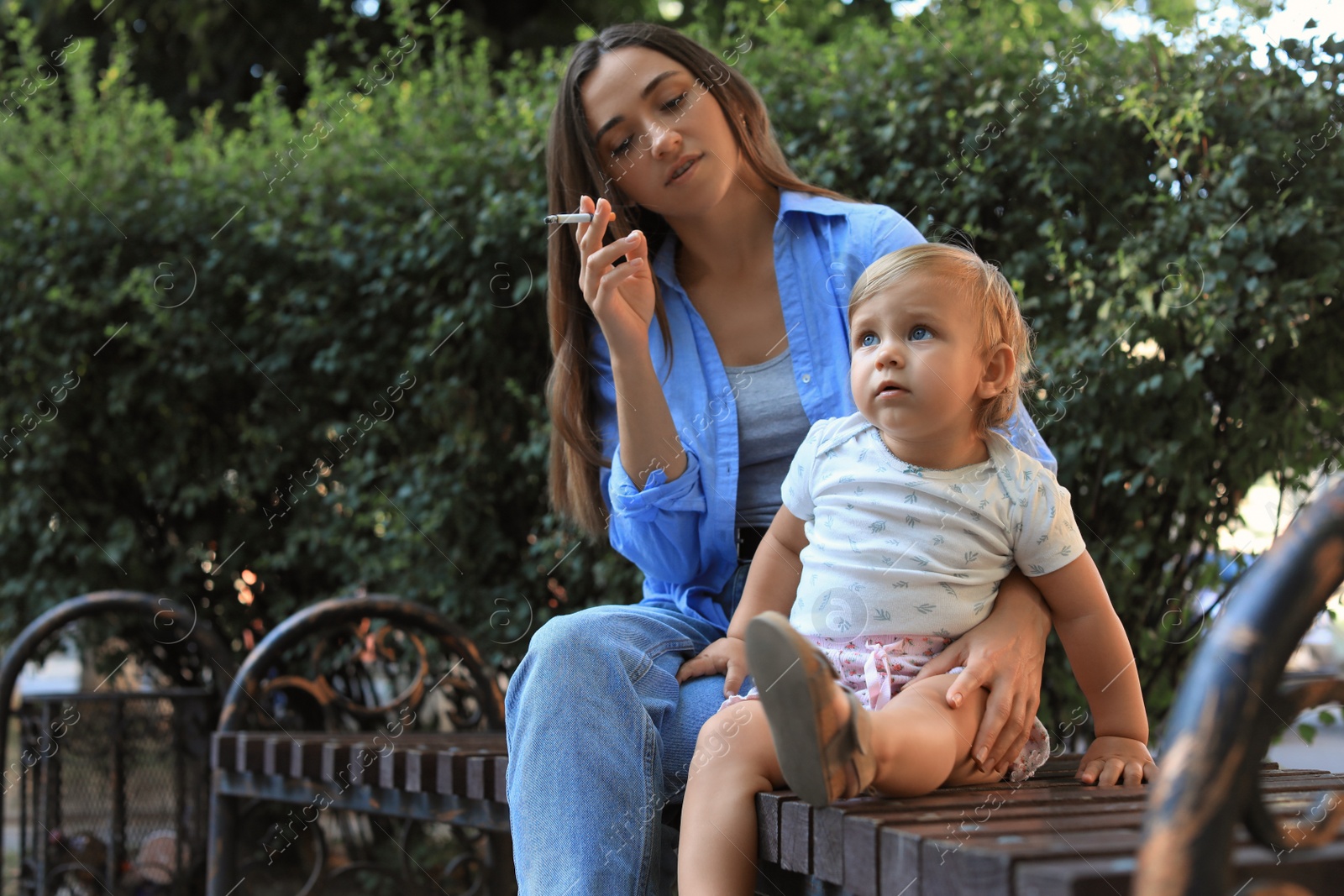 Photo of Mother with cigarette and child outdoors. Don't smoke near kids