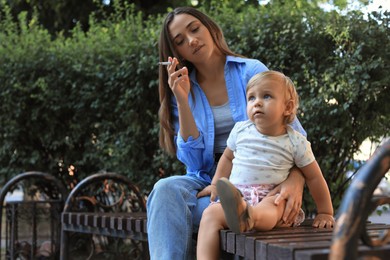 Mother with cigarette and child outdoors. Don't smoke near kids