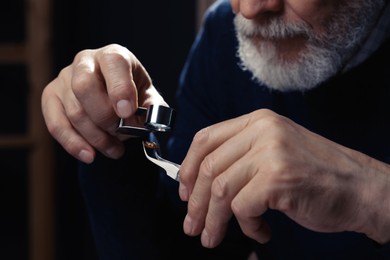 Professional jeweler working with gemstone on dark background, closeup