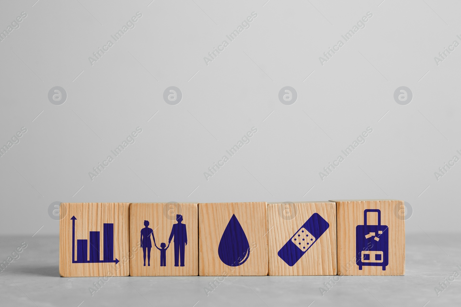 Image of Wooden cubes with different icons on light grey table, space for text. Insurance concept