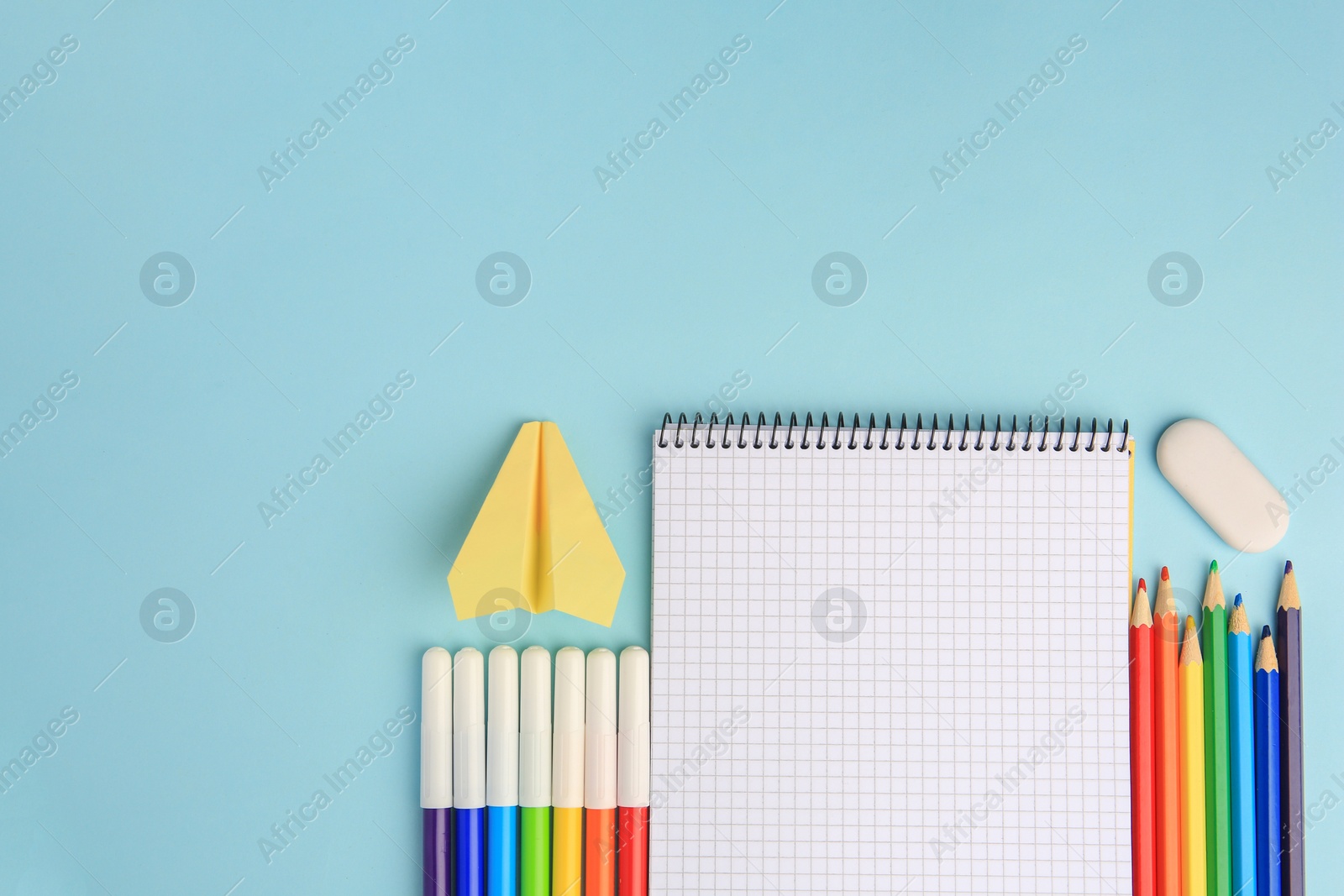 Photo of Flat lay composition with open notebook and other school stationery on light blue background, space for text. Back to school