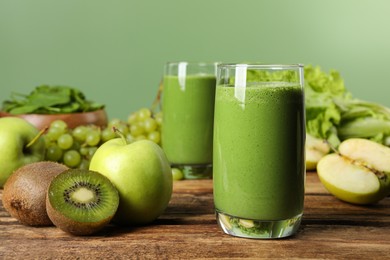 Photo of Green smoothie and fresh ingredients on wooden table. Space for text