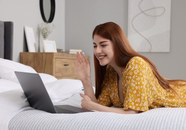Happy woman having video chat via laptop on bed in bedroom