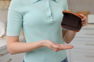 Woman with empty wallet at home, closeup