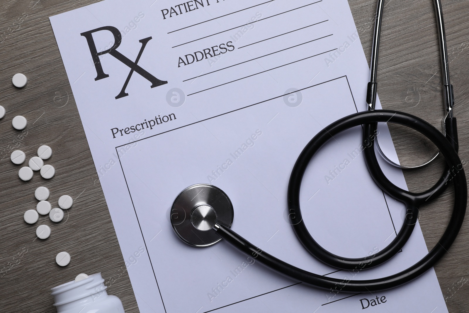 Photo of Medical prescription form, stethoscope and pills on wooden table, flat lay