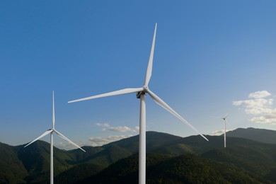 Image of Modern wind turbines in mountains on sunny day. Alternative energy source