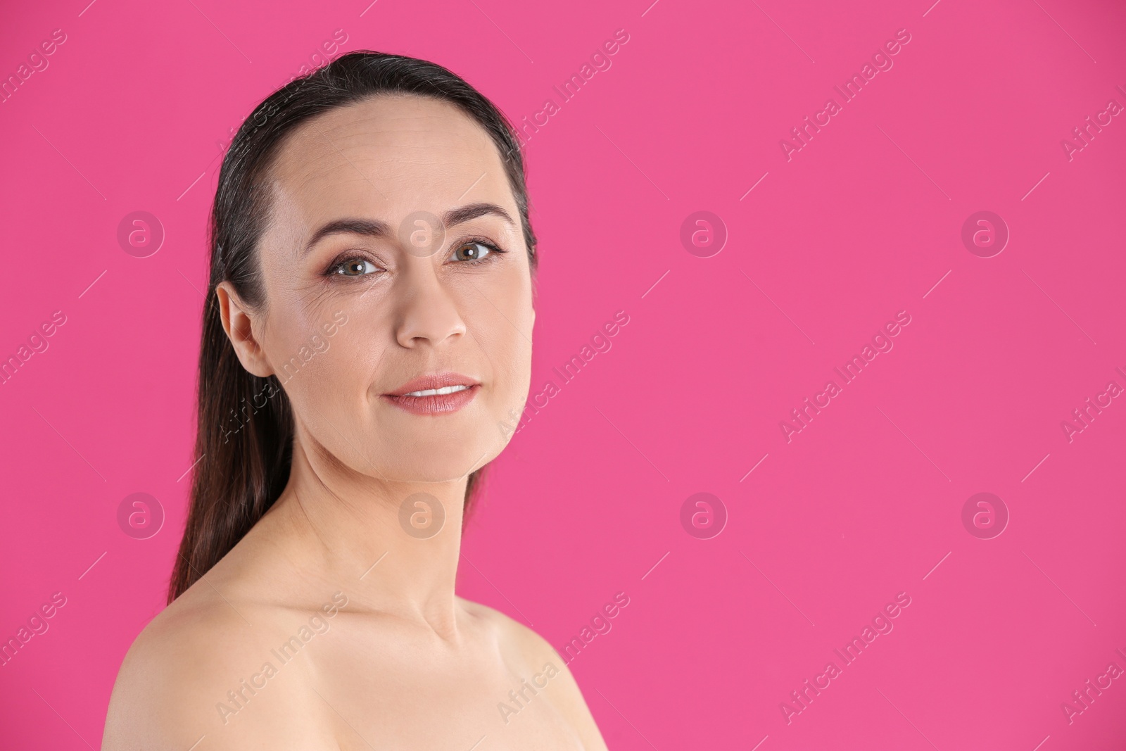 Photo of Portrait of beautiful mature woman on pink background. Space for text