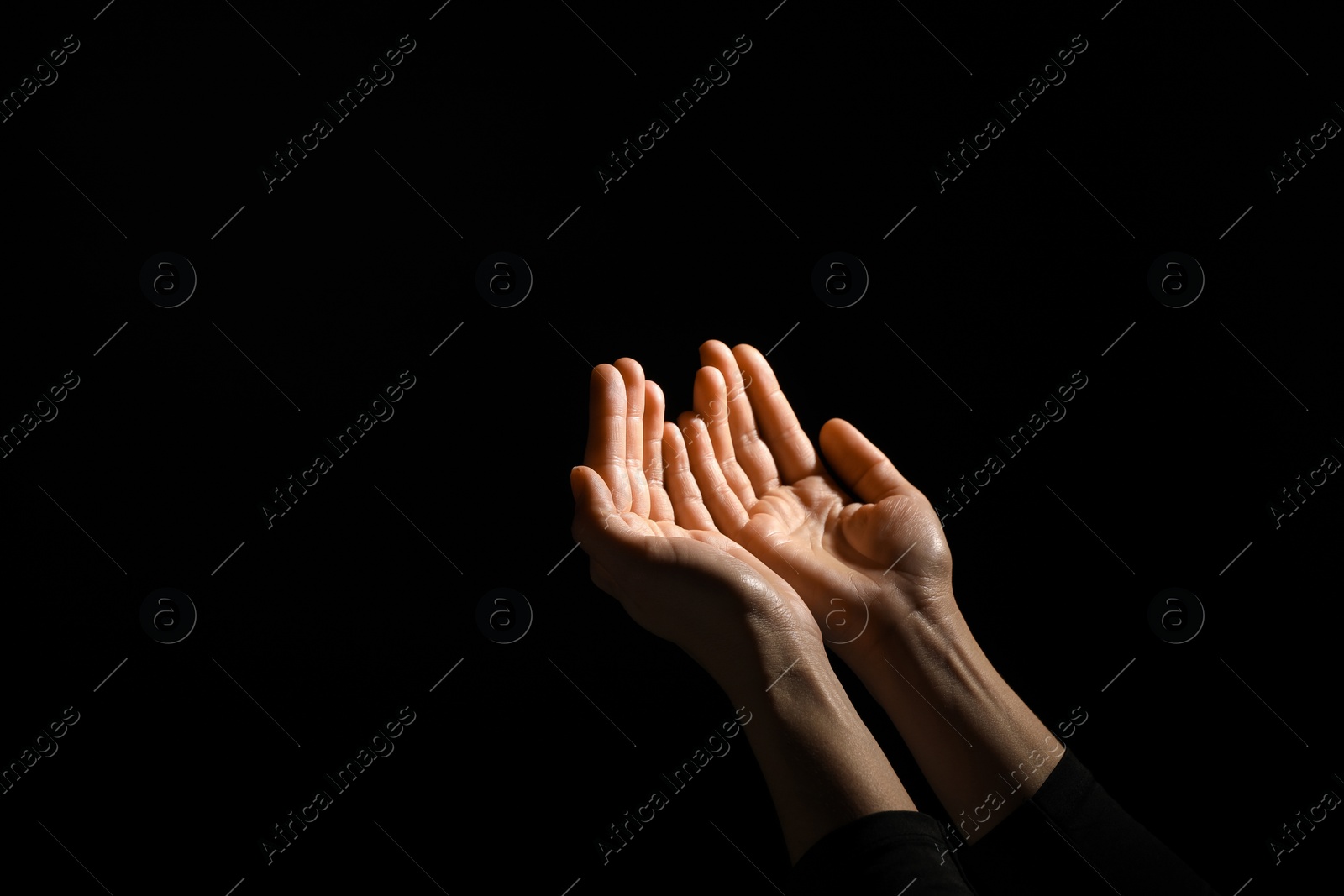 Photo of Religion. Woman with open palms praying on black background, closeup. Space for text