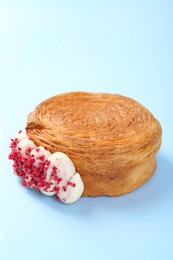 Photo of One supreme croissant with cream on light blue background. Tasty puff pastry