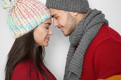 Photo of Young happy couple in warm clothes on light background. Christmas celebration