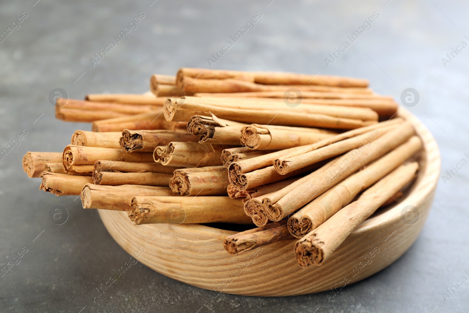 Photo of Aromatic cinnamon sticks on grey table, closeup