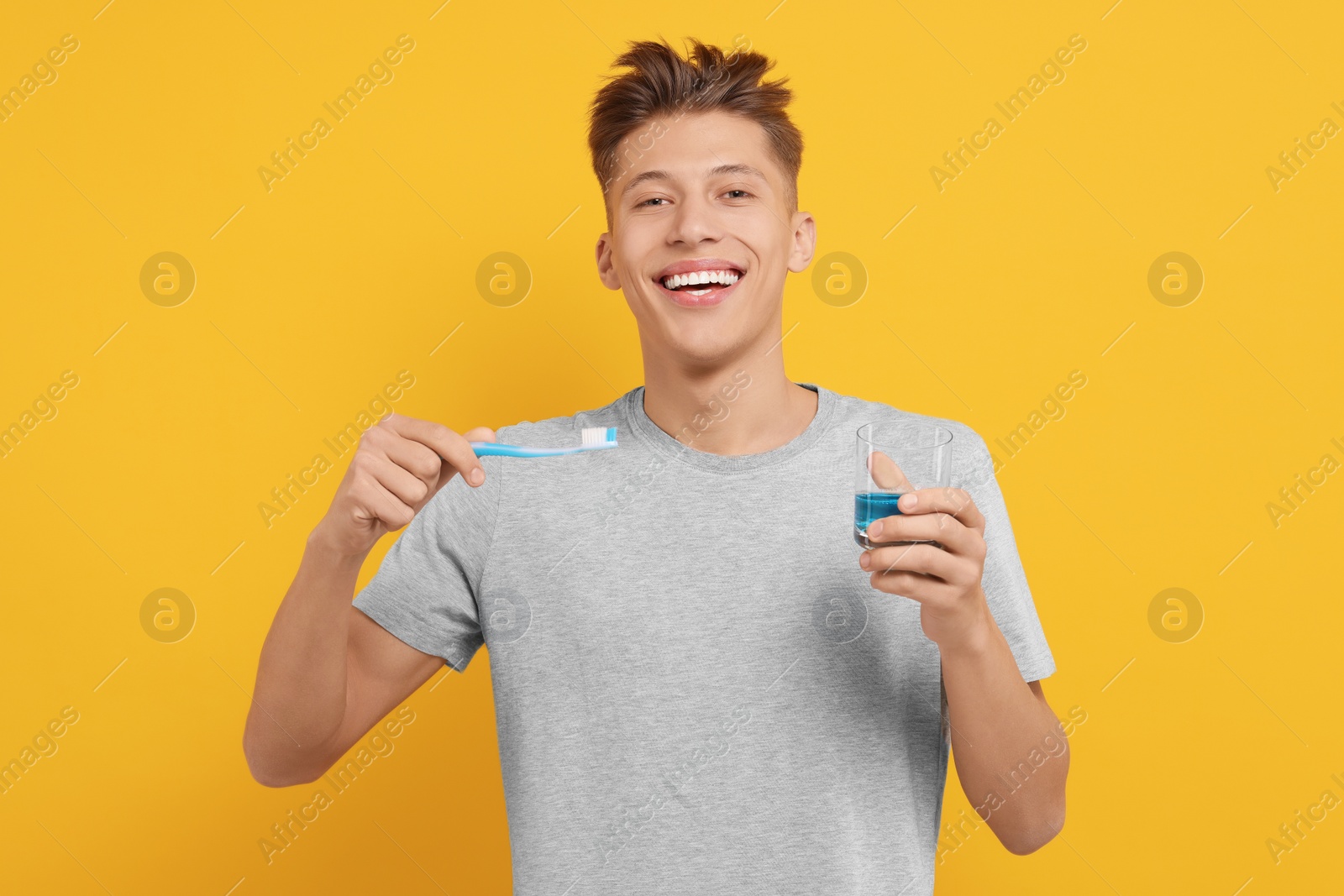 Photo of Young man with mouthwash and toothbrush on yellow background