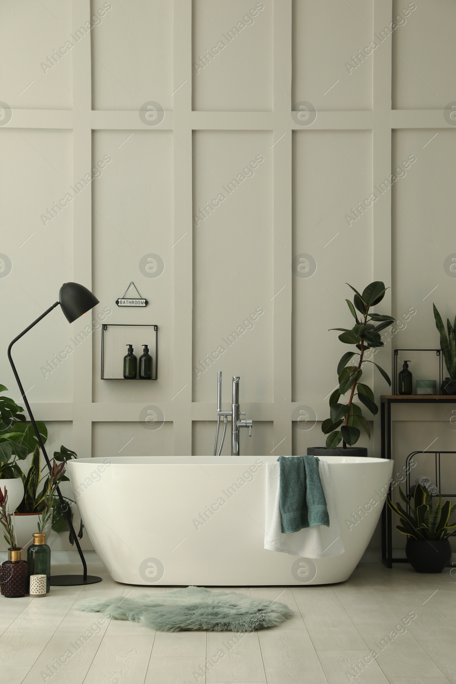 Photo of Stylish bathroom interior with modern tub and beautiful houseplants. Home design