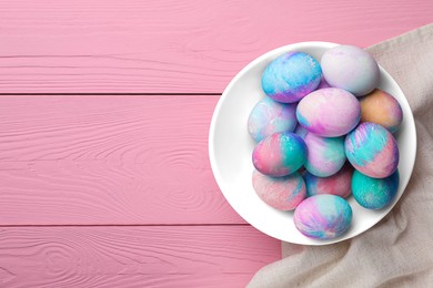 Photo of Bowl of decorated easter eggs on pink wooden table. top view. Space for text