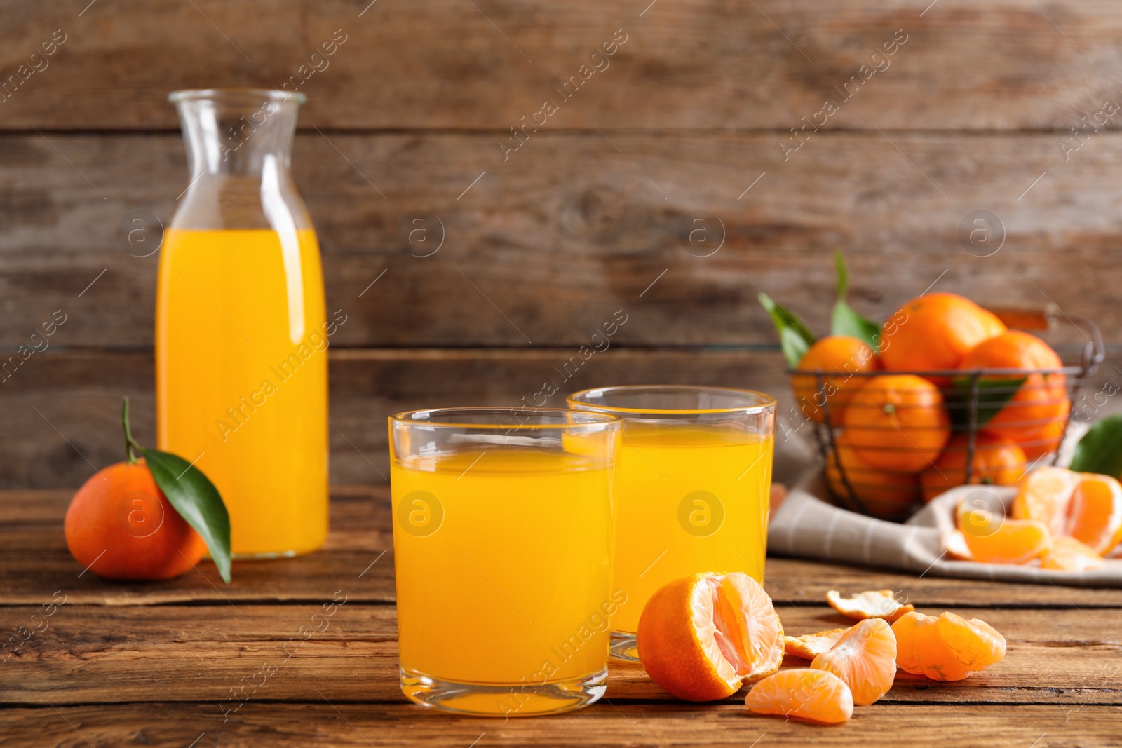 Photo of Glasses of fresh tangerine juice and fruits on wooden table