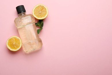 Photo of Mouthwash, mint and lemon on pink background, flat lay. Space for text