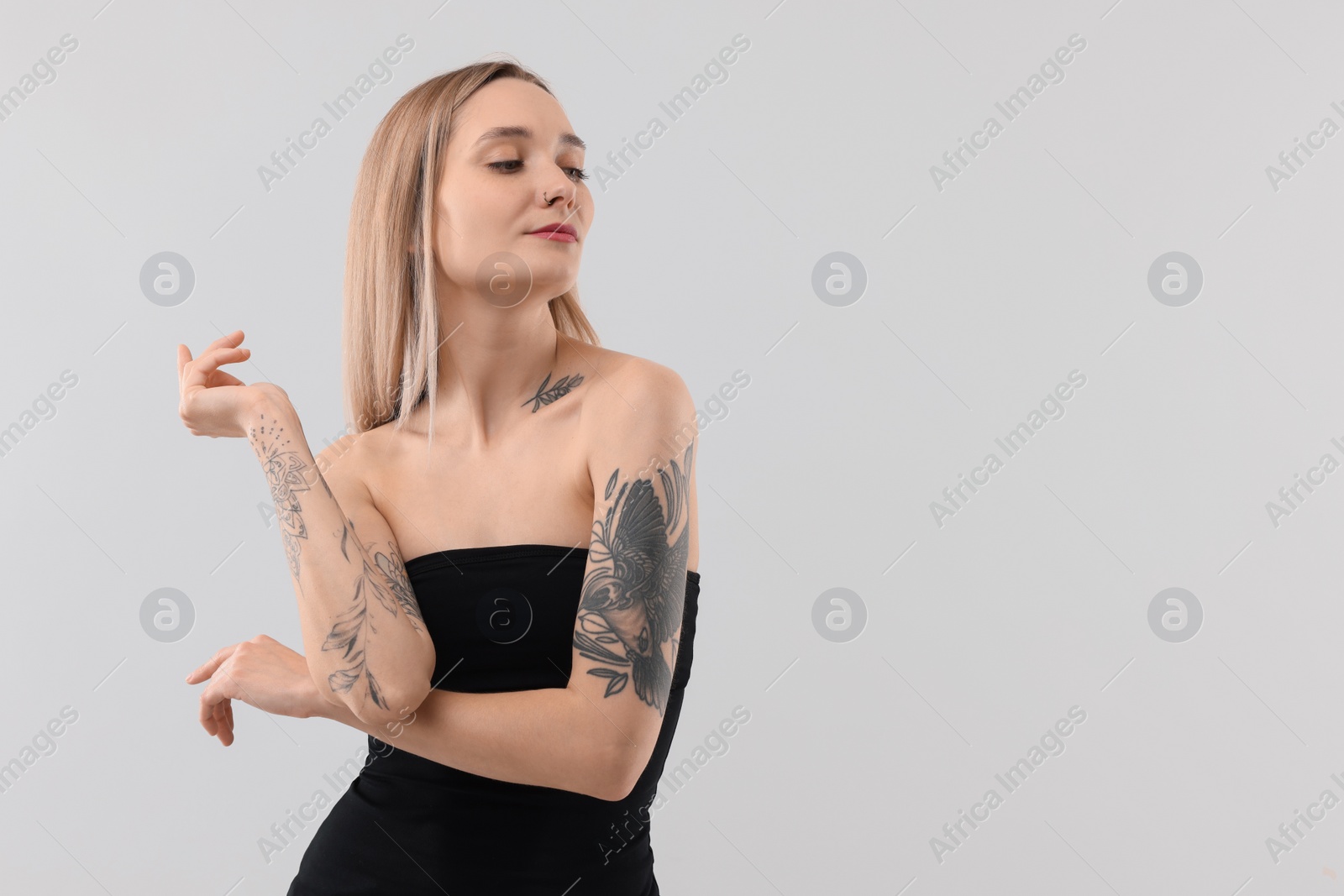 Photo of Beautiful tattooed woman on light background, space for text