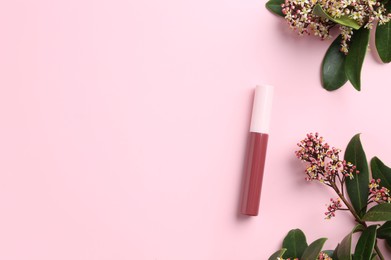 Photo of Bright lip gloss and flowering branches on pink background, top view. Space for text