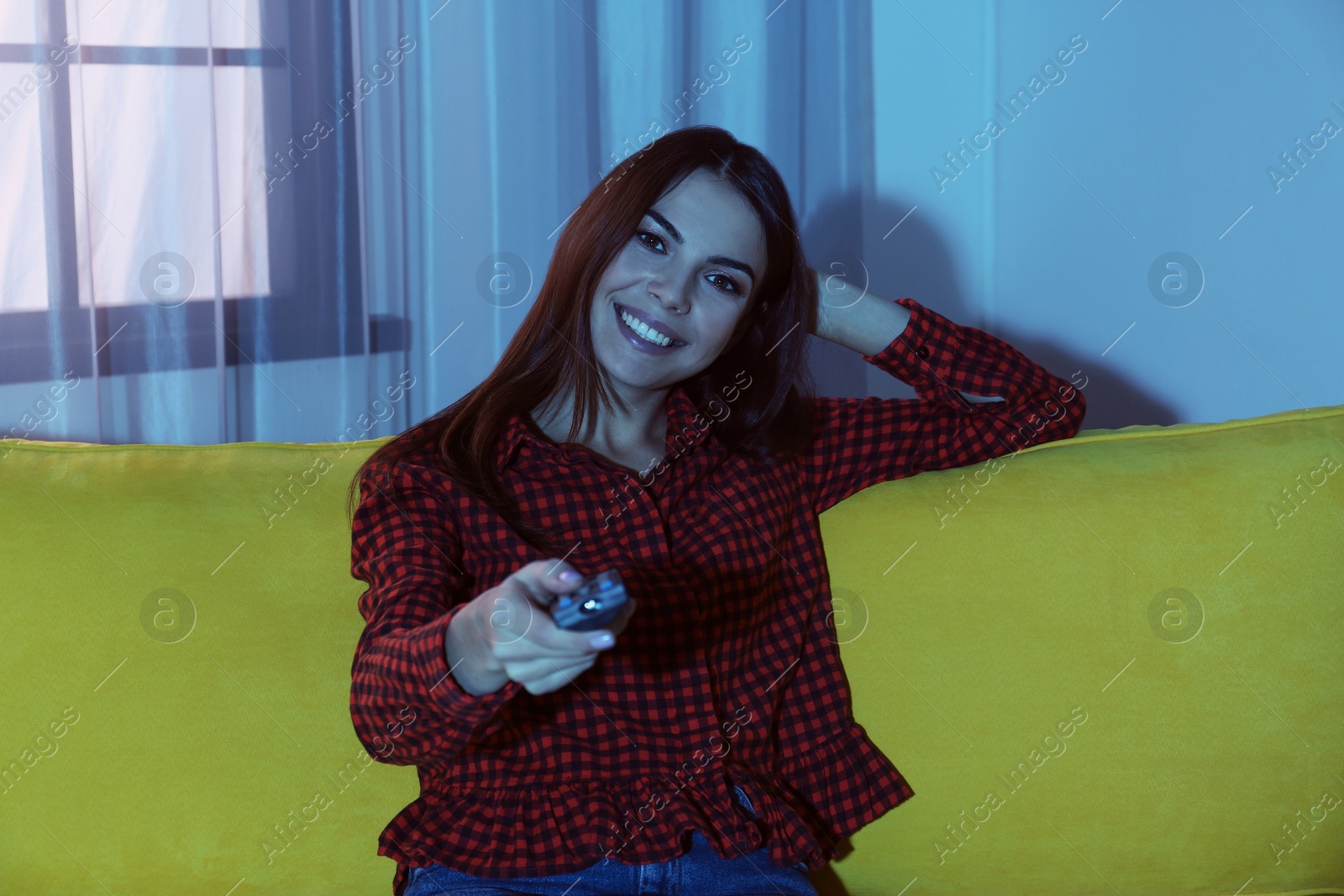 Photo of Beautiful young watching TV on sofa at home
