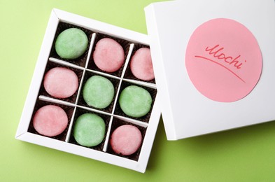Photo of Many different delicious mochi in box on green background, top view. Traditional Japanese dessert