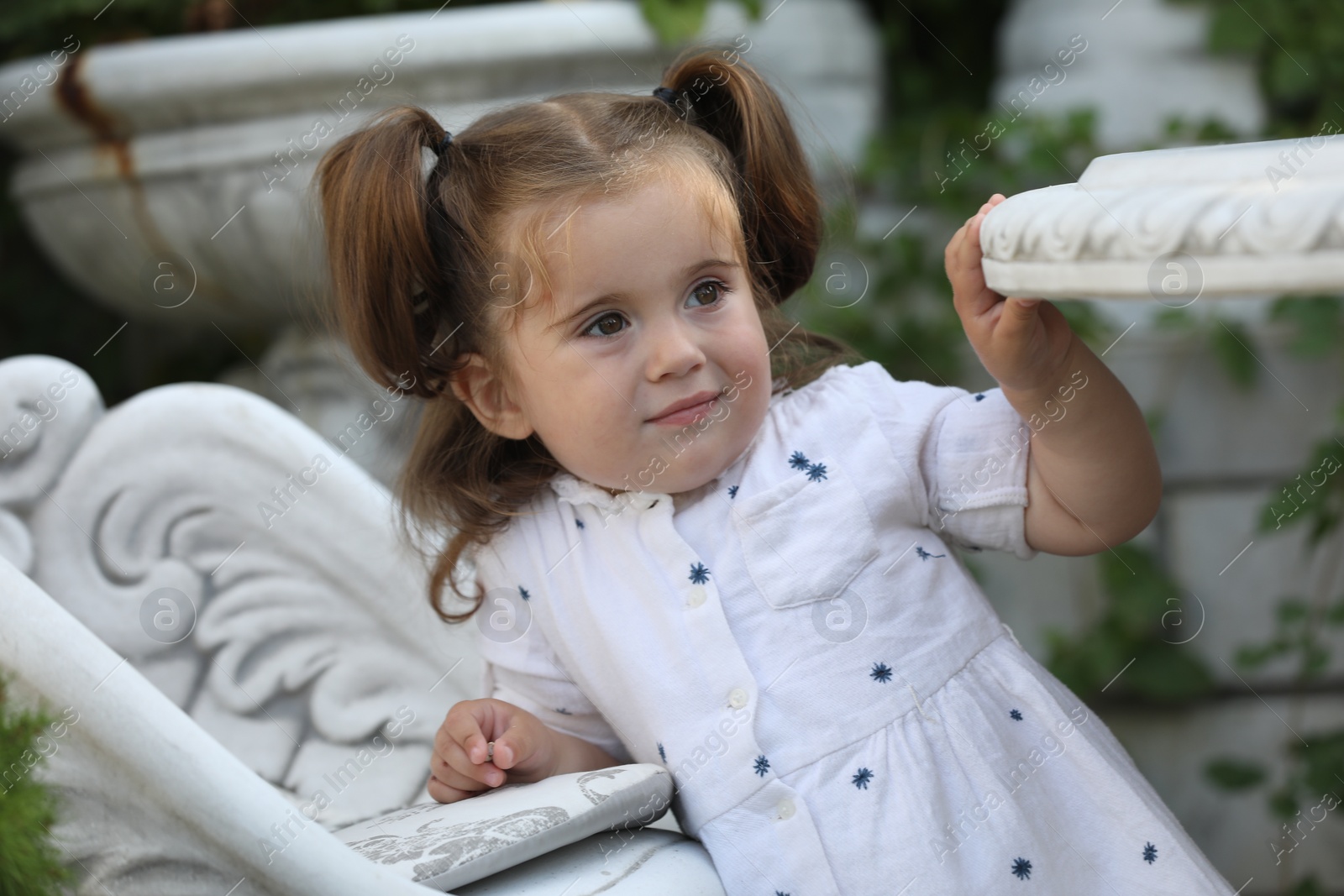 Photo of Portrait of cute little girl in white dress outdoors