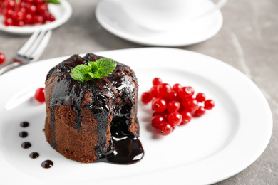 Delicious warm chocolate lava cake with mint and berries on plate, closeup