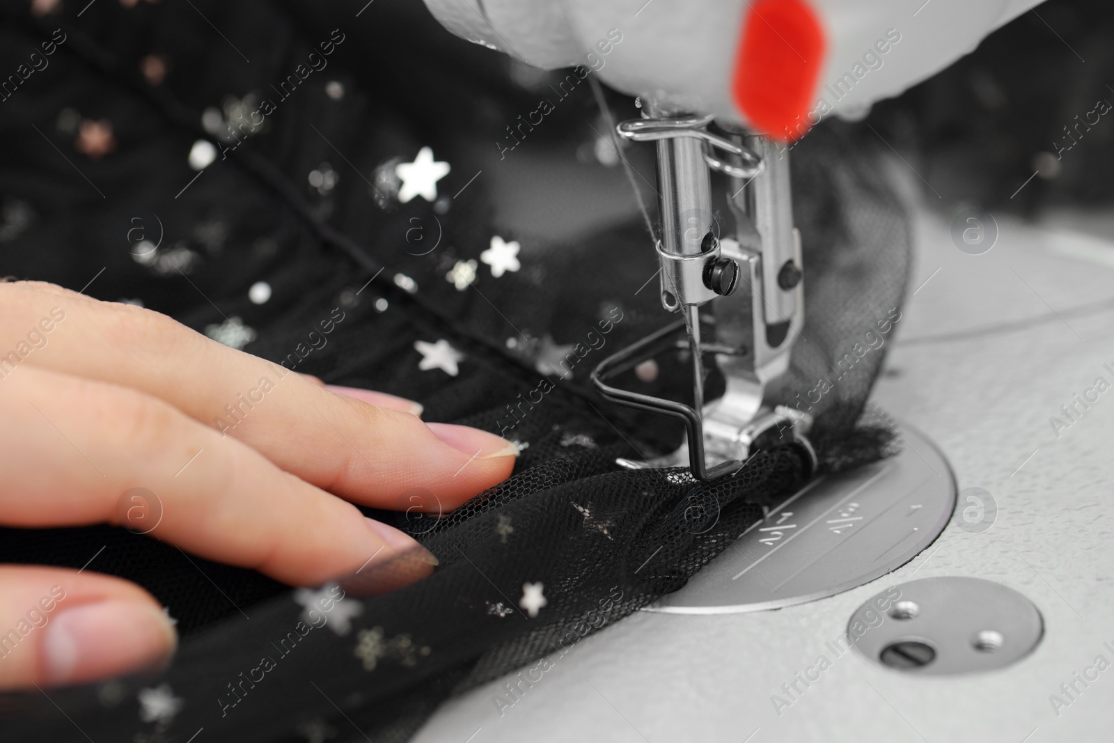 Photo of Dressmaker sewing new dress with machine in atelier, closeup